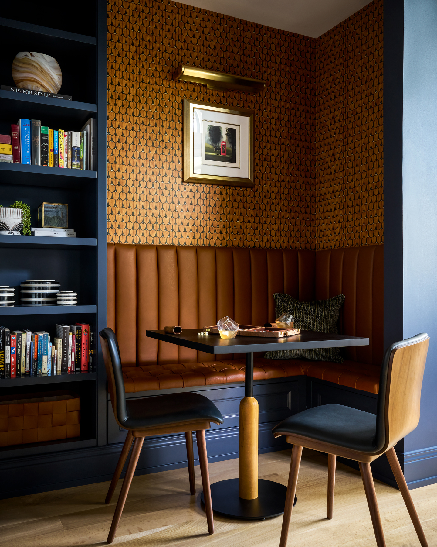 An intimate dining nook with a built-in booth and orange patterned wallpaper. Enhanced details and colors achieved with interior design retouching.