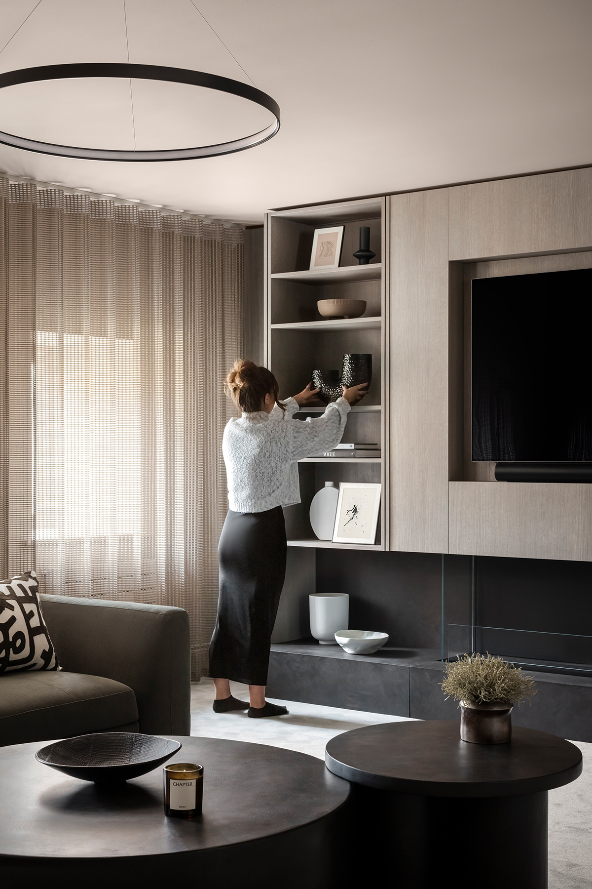 Detailed view of a modern living room with a custom shelving unit, showcasing carefully arranged decor items. Focus is on the balance and placement of objects within the built-in shelves.